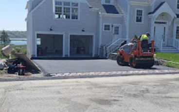 Driveway replacement in progress with heavy machinery removing old asphalt