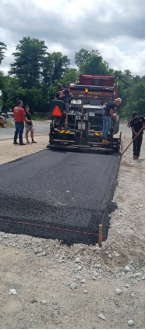 Asphalt paving crew operating paving machine during roadway installation