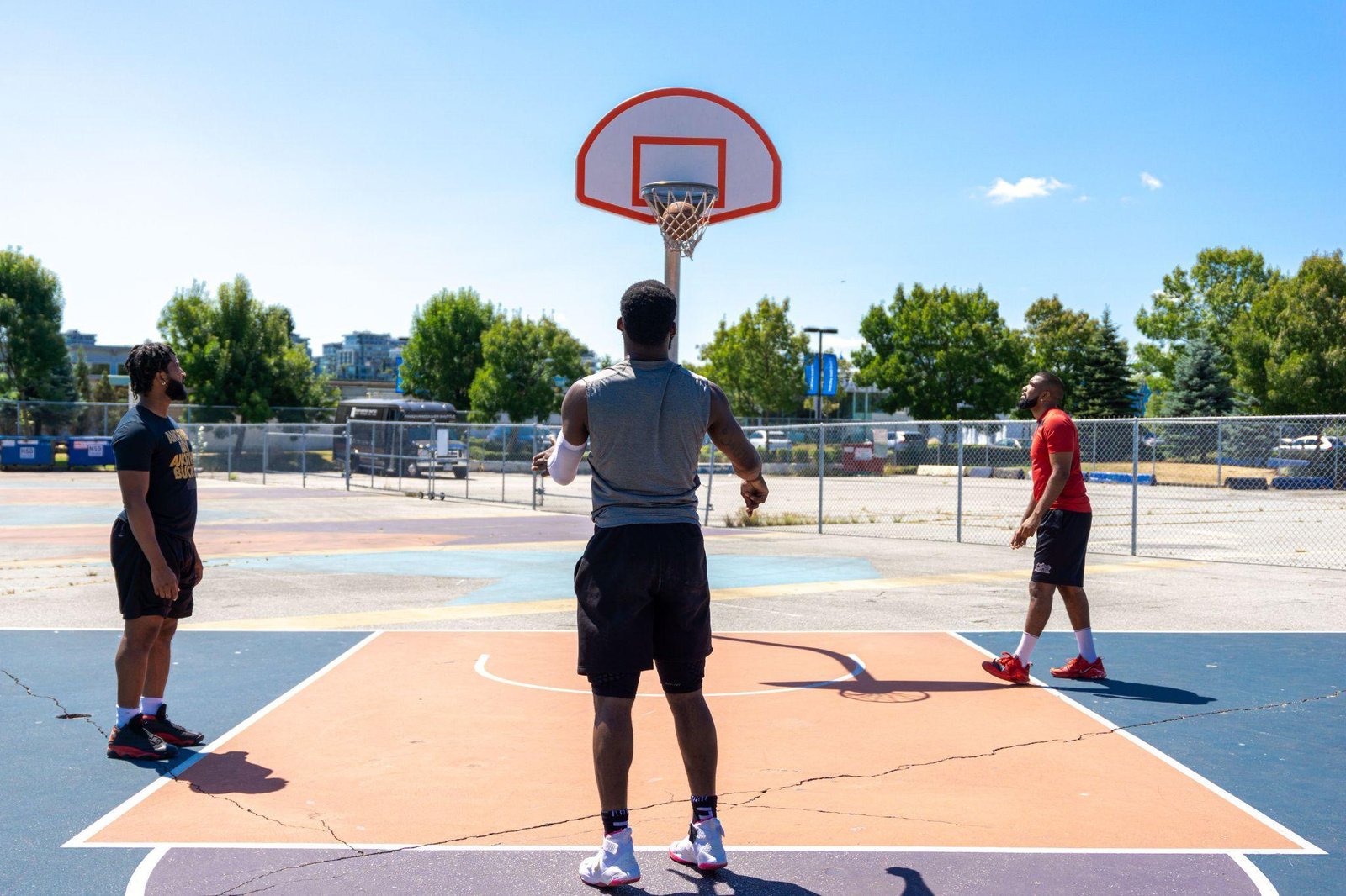 three people playing basketball on a court